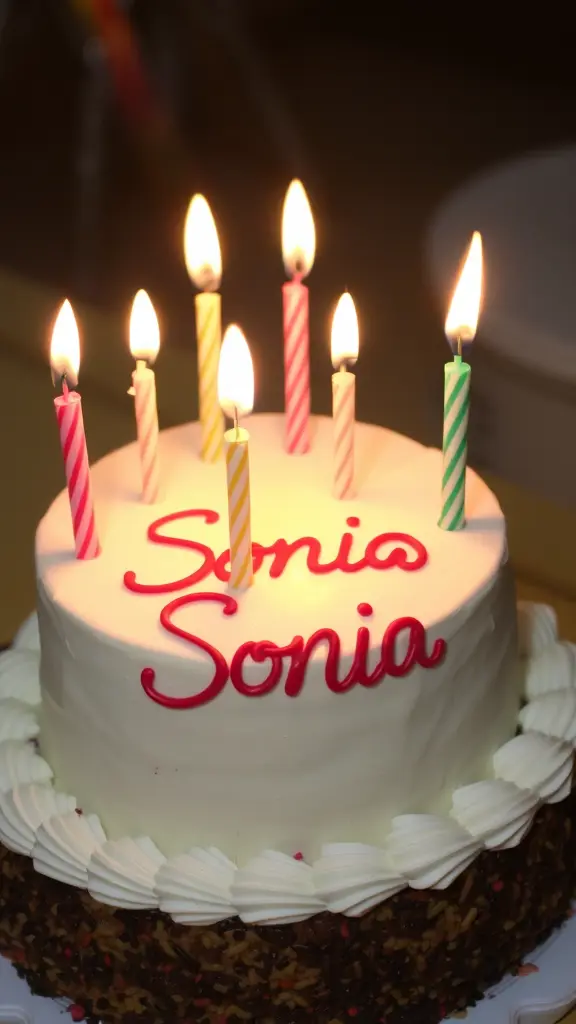 Birthday cake with Soso Sonia written on it, decorated with lit candles